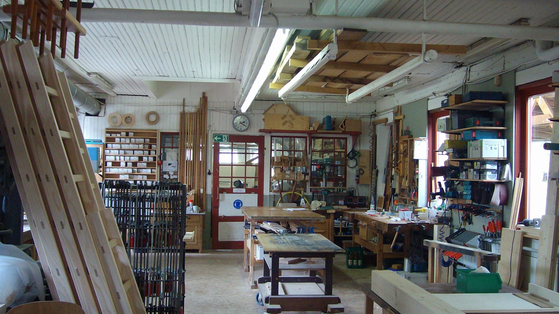 Wide view of an organ-building workshop interior with tools, pipe stock and benches