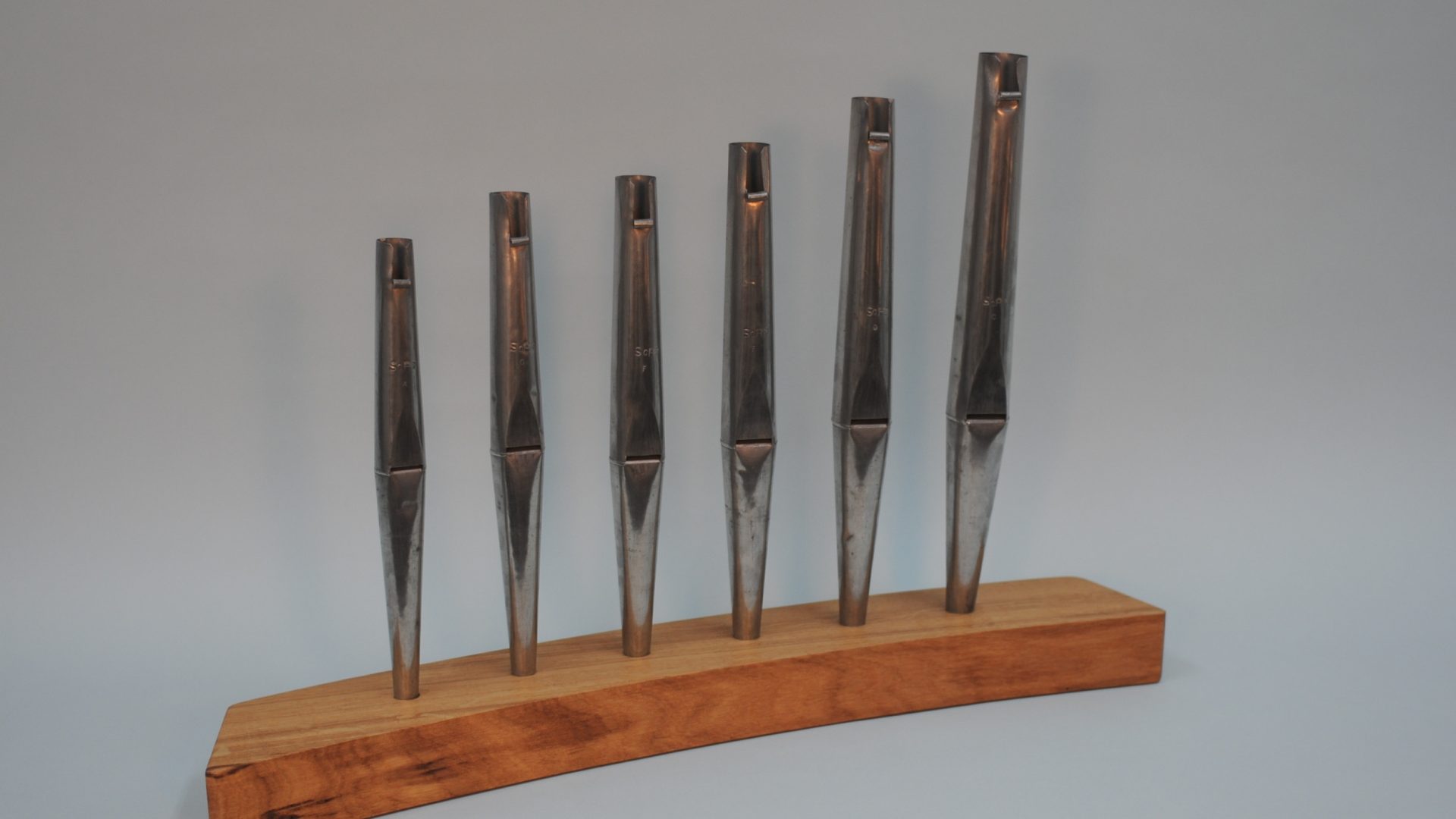 Six graduated metal principal pipes on a wooden test stand, part of a new organ build