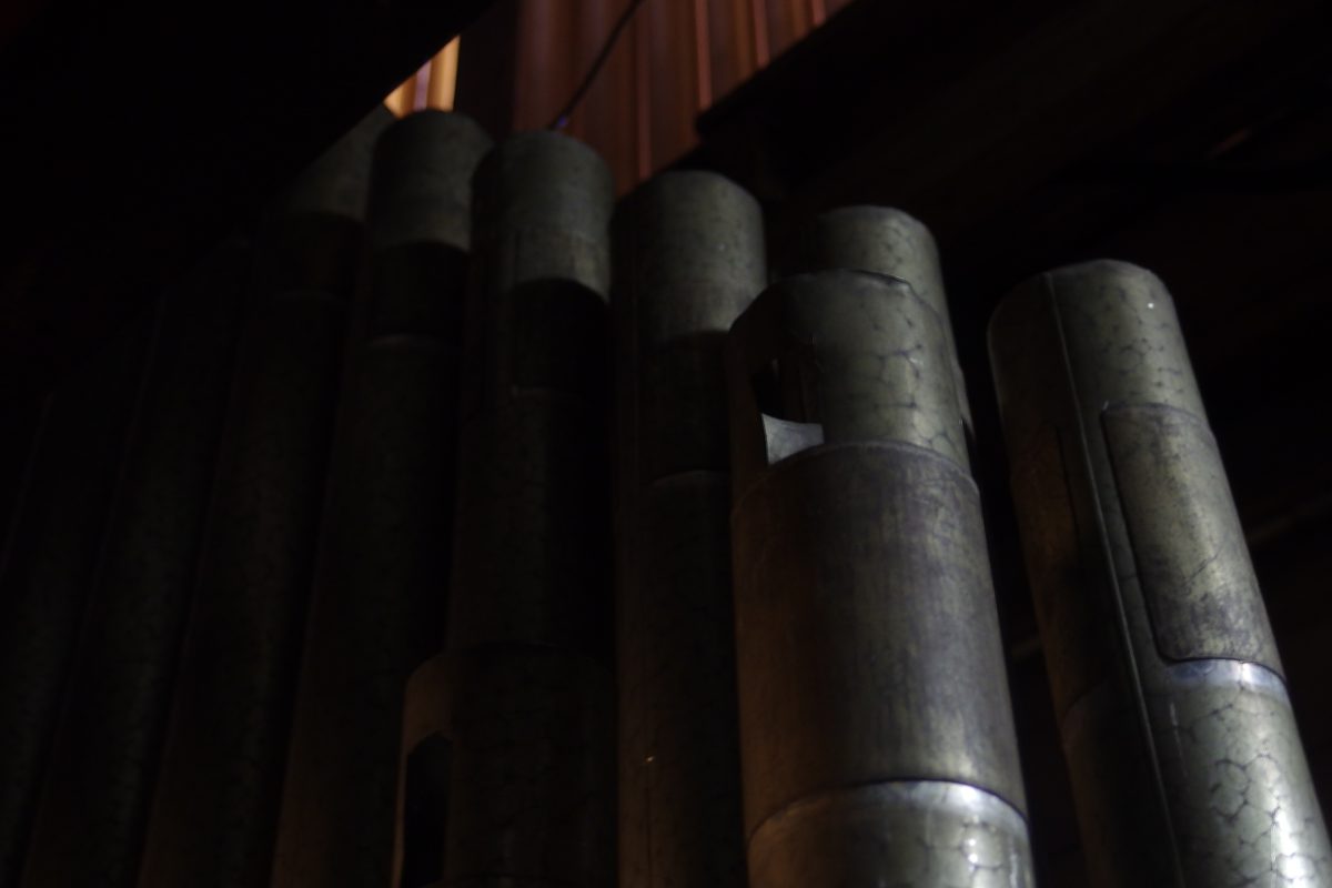 Detail of an historic pipe rank with round tuning holes and aged metal surface