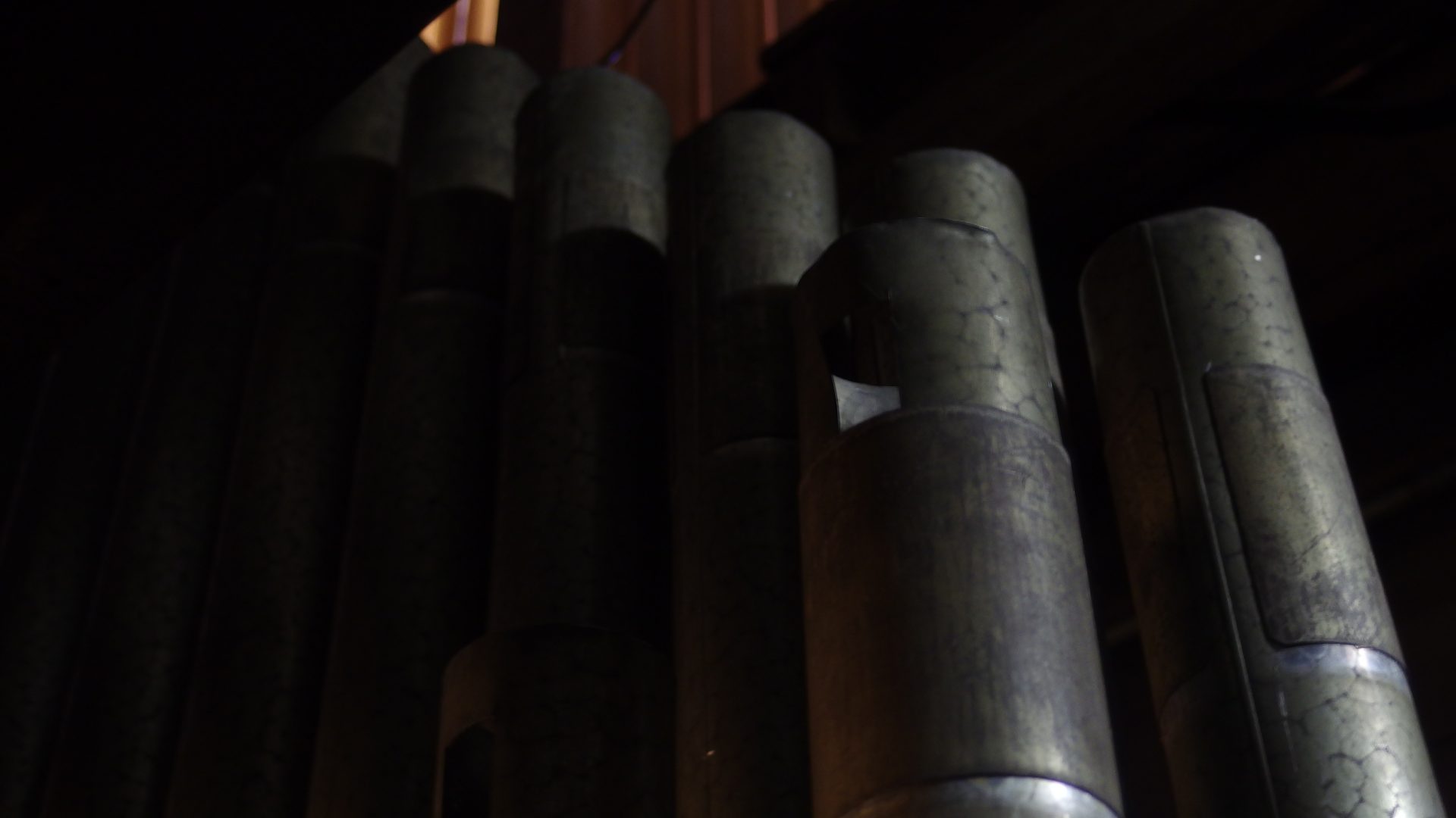 Detail of an historic pipe rank with round tuning holes and aged metal surface